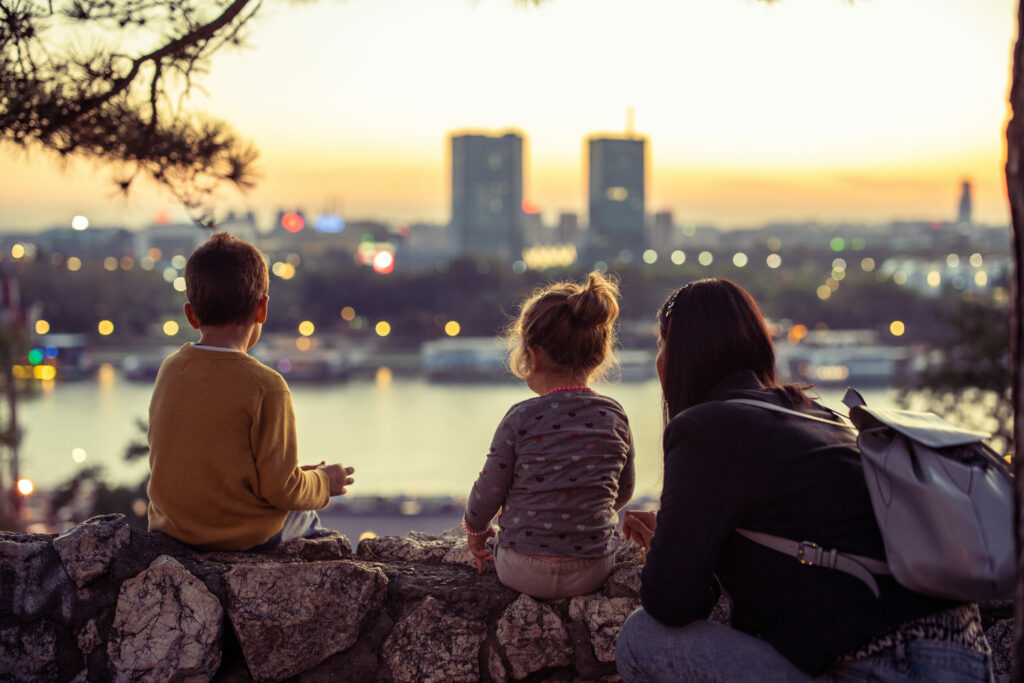 Mother with two kids sitting and looking cityscape from viewpoint